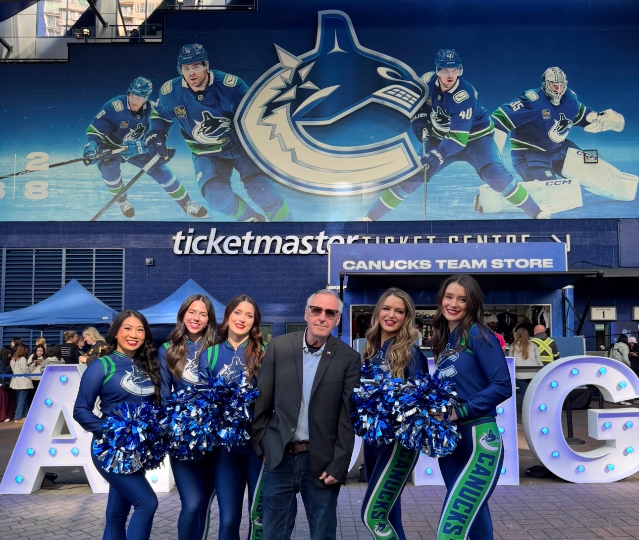 John standing with 5 Canucks cheerleaders.